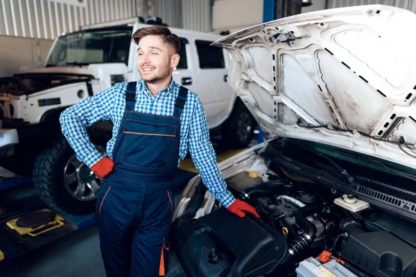 Un joven trabaja en una estación de servicio. El mecánico se dedica a reparar el coche . — Foto de Stock