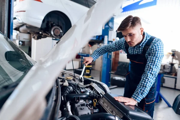 Молодой человек работает на заправке. Механик занимается ремонтом автомобиля . — стоковое фото