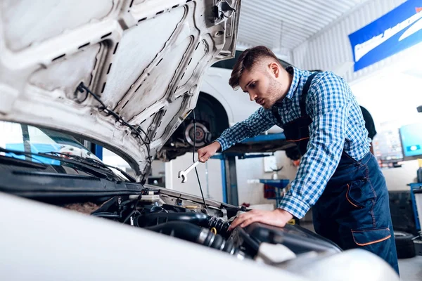 Un joven trabaja en una estación de servicio. El mecánico se dedica a reparar el coche . —  Fotos de Stock