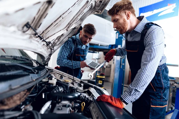 Vater und Sohn arbeiten beim Autoservice. Zwei Mechaniker arbeiten an den Details des Autos. — Stockfoto
