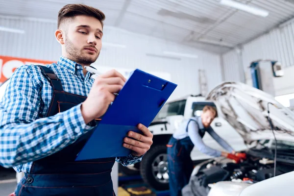 En ung man arbetar på en bensinstation. Mekanikern bedriver reparera bilen. — Stockfoto