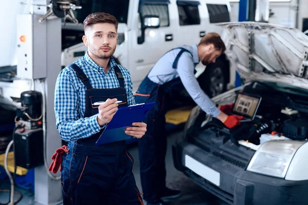 Father and son work at the auto service. Two mechanics work with the details of the car. — Stock Photo, Image