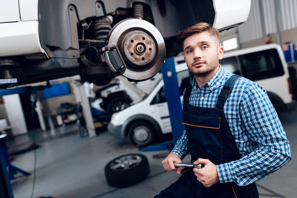 Молодий чоловік працює на станції обслуговування. Механік займається ремонтом автомобіля . — стокове фото