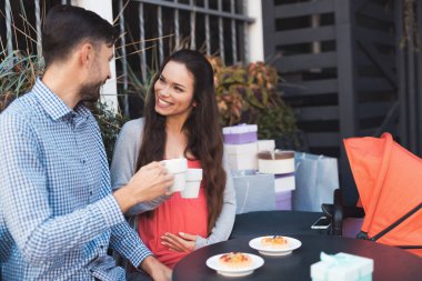 Hamile bir kadın bir erkekle bir kafe masada sokakta oturuyor.