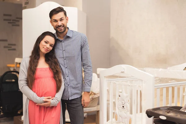 Eine schwangere Frau und ein Mann entscheiden sich für ein Kinderbett. — Stockfoto