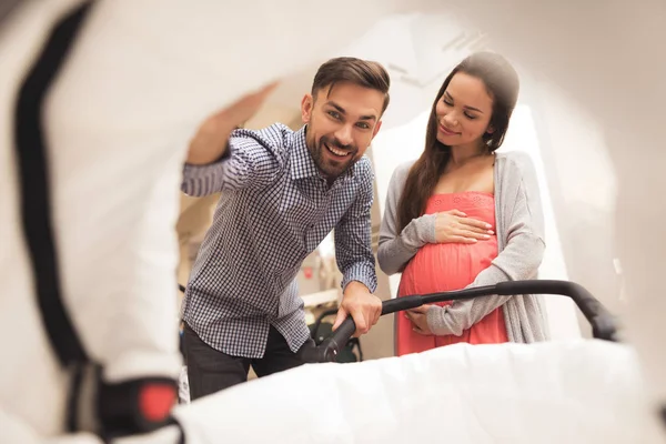 En gravid kvinna tillsammans med en man väljer en barnvagn. — Stockfoto