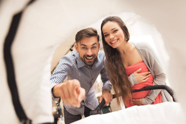 Беременная женщина вместе с мужчиной выбирают коляску
.