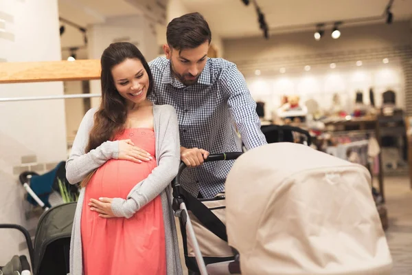 Kobiety w ciąży wraz z człowiekiem wybrać wózek dziecięcy. — Zdjęcie stockowe