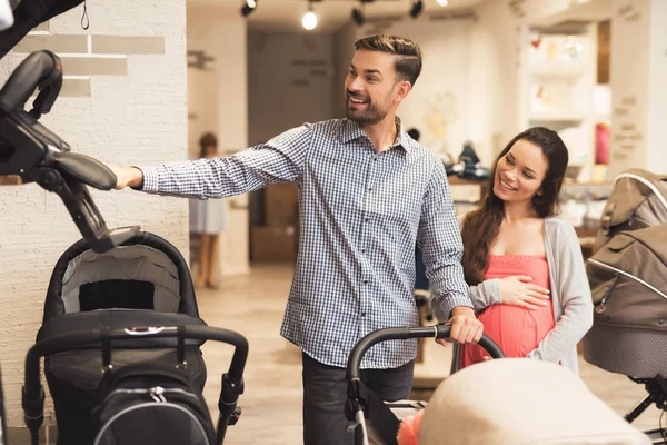 En gravid kvinna tillsammans med en man väljer en barnvagn. — Stockfoto