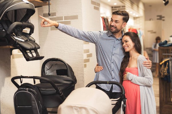 Беременная женщина вместе с мужчиной выбирают коляску
.