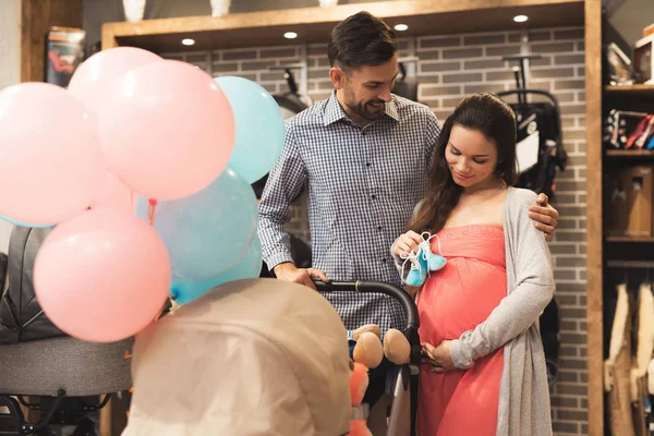 A pregnant woman together with a man choose a baby carriage. — Stock Photo, Image