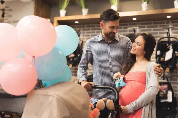 Eine schwangere Frau und ein Mann entscheiden sich für einen Kinderwagen. — Stockfoto