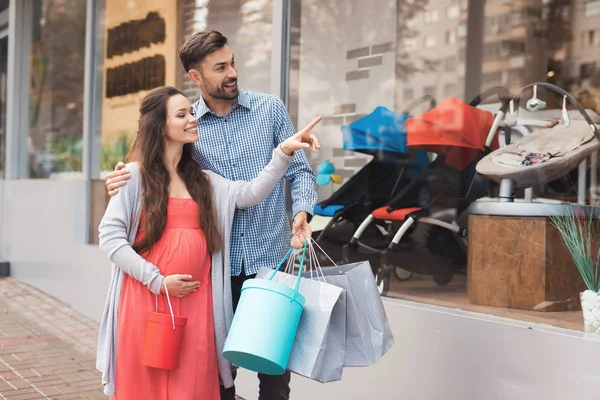 Vitrin çocuk mal ile geçmiş yürüyen bir adam hamile bir kadınla.
