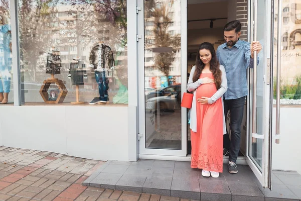 En man och en gravid kvinna lämnar butiken. — Stockfoto