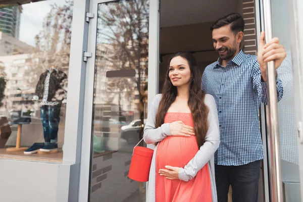 En man och en gravid kvinna lämnar butiken. — Stockfoto