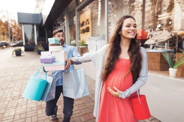 Une femme enceinte avec un homme passant devant la vitrine avec des articles pour enfants . — Photo