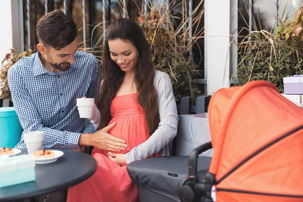 Eine schwangere Frau mit einem Mann sitzt an einem Cafétisch auf der Straße. — Stockfoto