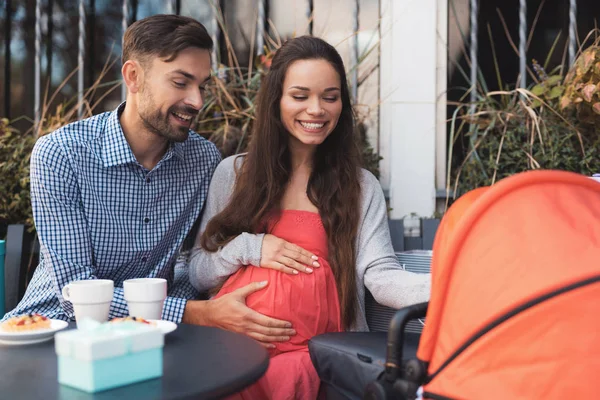 Těhotná žena s mužem je sedět u stolu kavárny na ulici. — Stock fotografie