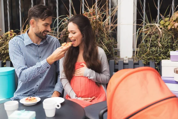 A pregnant woman with a man is sitting at a cafe table on the street. — Stock Photo, Image