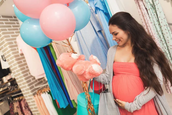 Una mujer embarazada elige productos para bebés en la tienda . — Foto de Stock