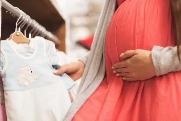 Una mujer embarazada elige productos para bebés en la tienda . — Foto de Stock