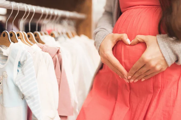 Uma mulher grávida escolhe bens de bebê na loja . — Fotografia de Stock