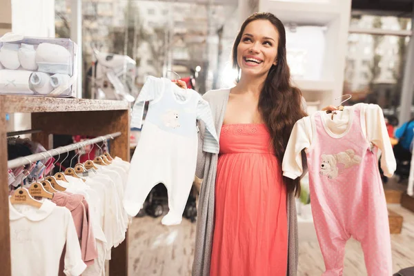 Una mujer embarazada elige productos para bebés en la tienda . — Foto de Stock