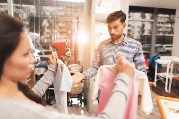 En gravid kvinne med en mann velger barnetøy i butikken. . – stockfoto