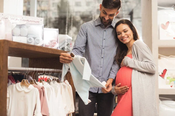 Una donna incinta con un uomo sceglie beni per bambini nel negozio . — Foto Stock