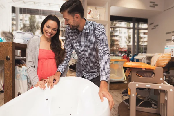 Une femme enceinte avec un homme choisir un bain de bébé dans un magasin . — Photo