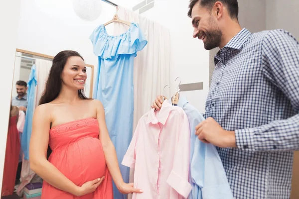 Hamile bir kadın bir erkekle giysiler içinde belgili tanımlık stok seçer.. — Stok fotoğraf