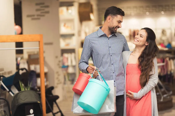 Una mujer embarazada y un hombre posan para una cámara con productos en un centro comercial . — Foto de Stock