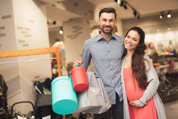 Una mujer embarazada y un hombre posan para una cámara con productos en un centro comercial . — Foto de Stock