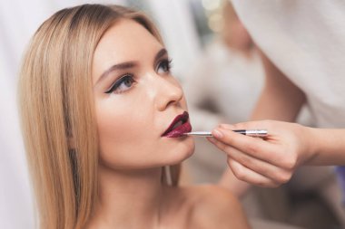 Sarışın bir kız makyaj güzellik salonunda verilir. Kız visagiste tarafından dudakları ile boyalı.