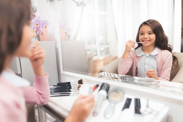 Mooie meisje in de schoonheidssalon. Het meisje maakt zelf een make-up. Ze glimlacht en houdt van te laten uitzien als haar moeder. — Stockfoto