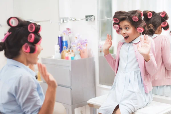 Moeder en dochter in een schoonheidssalon. Ze hebben krulspelden in hun haar. Ze uiten hun vreugdevolle emoties — Stockfoto