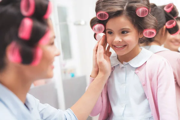 Moeder en dochter in een schoonheidssalon. Ze hebben krulspelden in hun haar. Moeder bewondert haar mooie dochter. — Stockfoto