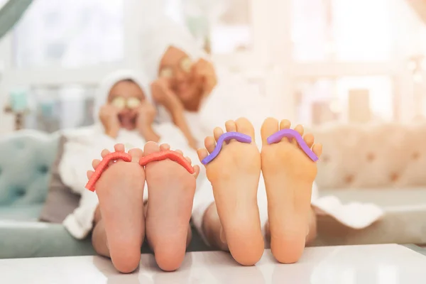 Close-up foto van dochter en moeder met spons voor pedicure op vingers. Ze gelezen tijdschriften in witte badjassen. — Stockfoto