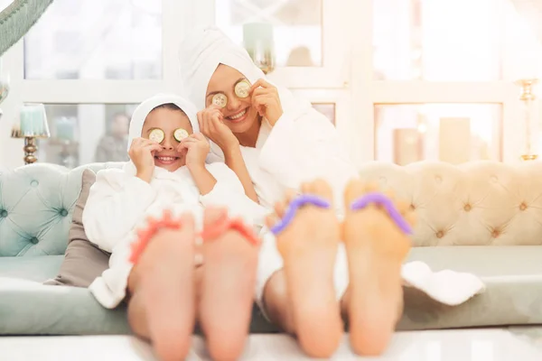 Nahaufnahme von Tochter und Mutter mit Schwamm für Pediküre an den Fingern. Sie lesen Zeitschriften in weißen Bademänteln. — Stockfoto