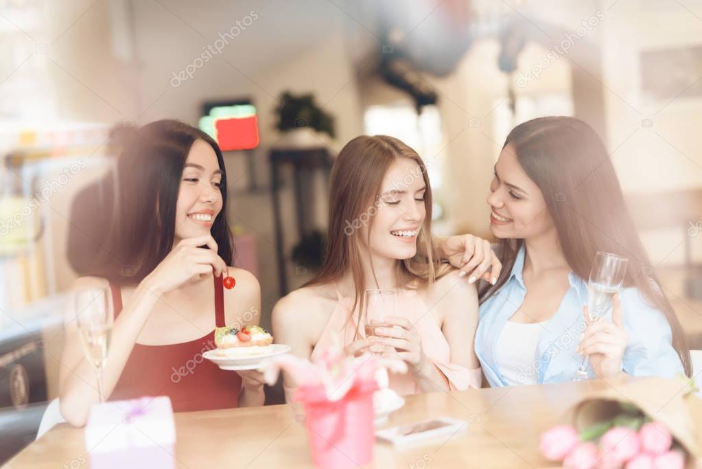 Three girls are sitting together in a cafe.