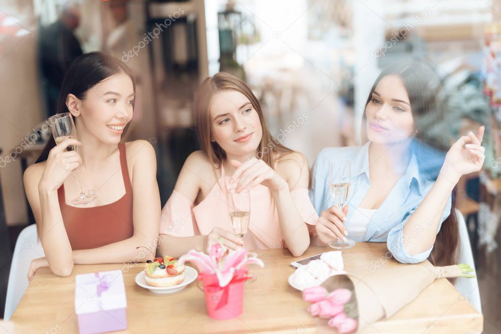 Three girls are sitting together in a cafe.