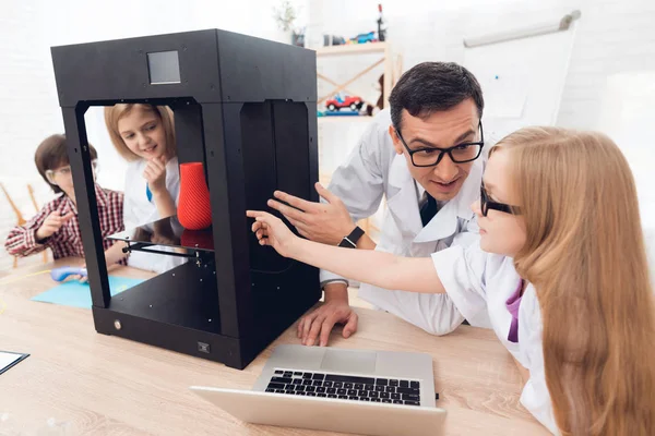 Los niños imprimen diferentes artículos en una impresora 3D con un maestro . —  Fotos de Stock