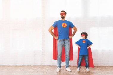 Baba ve oğul süper kahramanlar kırmızı ve mavi elbiseli. Üzerinde yüzlerini maskeleri ve onlar içinde yağmurluklar.