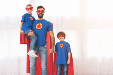 Süper kahramanlar kırmızı ve mavi elbiseli çocuklu baba. Onlar maskeleri ve yağmurluklar.