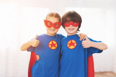 Süper kahramanlar kırmızı ve mavi elbiseli çocuklar. Onlar maskeler. Aydınlık salonda poz çocuklar.