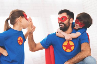 Süper kahramanlar kırmızı ve mavi elbiseli çocuklu baba. Onlar maskeleri ve yağmurluklar.