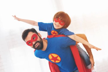 Baba ve oğul süper kahramanlar kırmızı ve mavi elbiseli. Üzerinde yüzlerini maskeleri ve onlar içinde yağmurluklar.