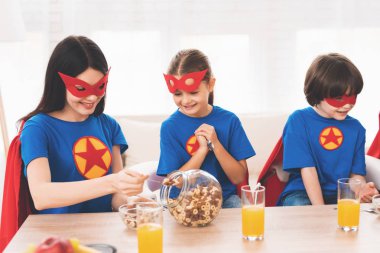 Süper kahramanlar kırmızı ve mavi elbiseli çocuk anne. Onlar maskeleri ve yağmurluklar.