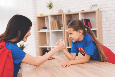 Anne ve kızı süper kahramanlar takım elbiseli. Arm-wrestling içinde rekabet