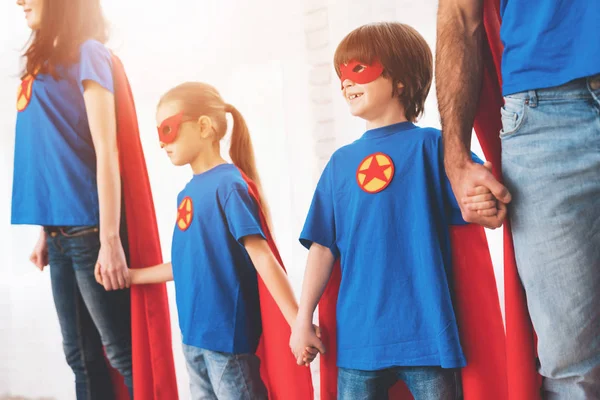 年轻的家庭在红色和蓝色的超级英雄的西装。他们的面孔在面具和他们在雨衣. — 图库照片